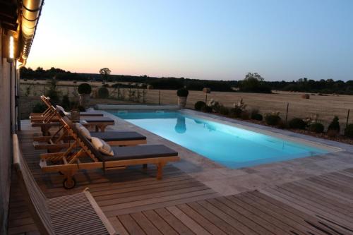 a swimming pool on a wooden deck with lounge chairs around it at Le Montillon in Tour-en-Sologne
