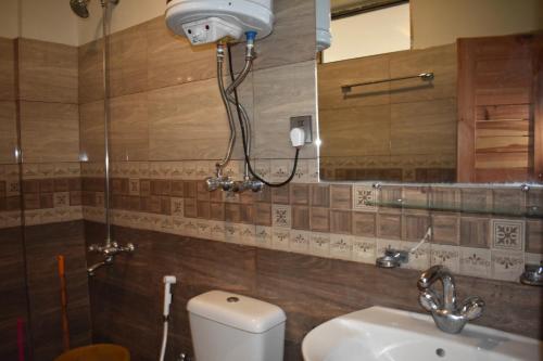 een badkamer met een toilet, een wastafel en een spiegel bij Hotel Royal Inn in Murree