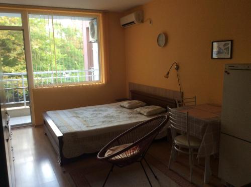 a bedroom with a bed and a table and a window at Marina Studio in Burgas
