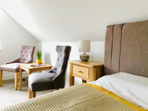 a bedroom with two chairs and a bed and a table at 'Sea Breeze' Dorset dream holiday home in Poole
