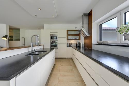 a kitchen with white cabinets and black counter tops at Ferienwohnung Panorama Eg in Inzell