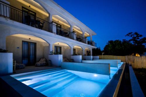 a villa with a swimming pool at night at Agave Boutique Hotel in Laganas