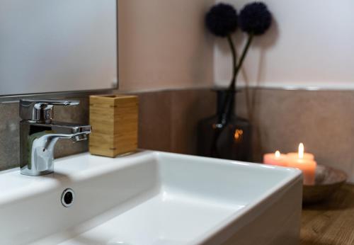 a white sink with a candle and a vase with a flower at Casa Tina Holiday Home in Diano dʼAlba