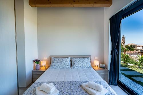 a bedroom with a bed and a large window at Casa Tina Holiday Home in Diano dʼAlba