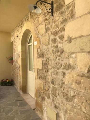 a stone wall with a white door and a window at Domo Antiga Guest Rooms in Sorso