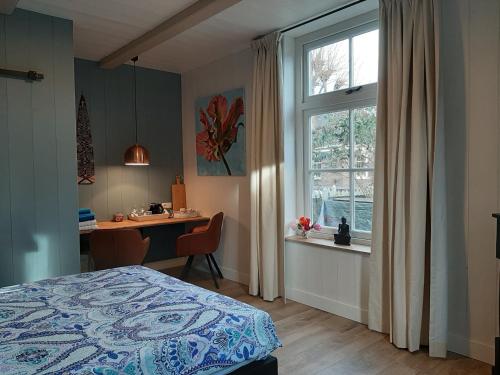a bedroom with a bed and a desk and a window at B & B Tulp Amsterdam Noord in Amsterdam