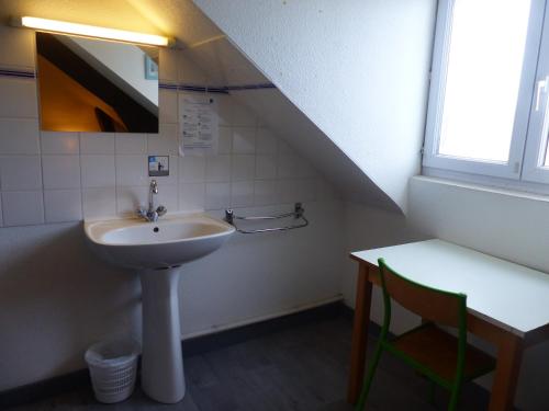 a bathroom with a sink and a table with a chair at Auberge de Jeunesse HI Pontivy in Pontivy