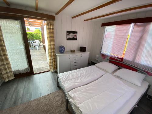 1 dormitorio con cama blanca y balcón en Ferienpark Vislust Haus Angel Niederlande Ijsselmeer, en Wervershoof