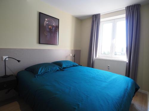 Un dormitorio con una cama azul y una ventana. en ENA 3 pièces neuf entre centre et gare, en Estrasburgo