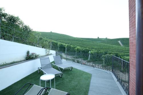 a patio with chairs and tables on a balcony with vineyards at Villa Giobatta in Barolo