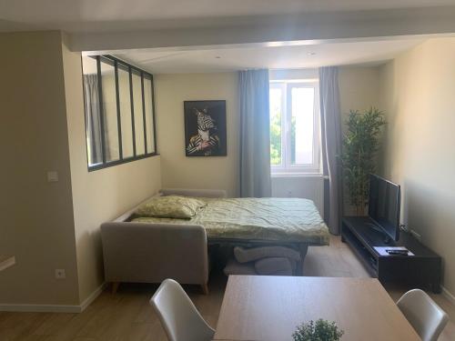 Una sala de estar con una mesa y sillas y un televisor. en ENA 3 pièces neuf entre centre et gare, en Estrasburgo