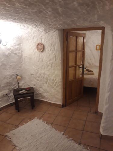 una stanza con una porta e un tavolo con un tappeto di The Welcome Cave a Freila