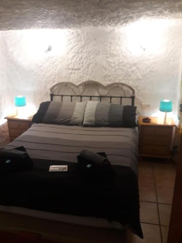 a bedroom with a bed with two lamps on two tables at The Welcome Cave in Freila