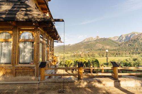 una cabaña con una valla y montañas al fondo en Podhalańskie Tarasy by LoftAffair en Kościelisko