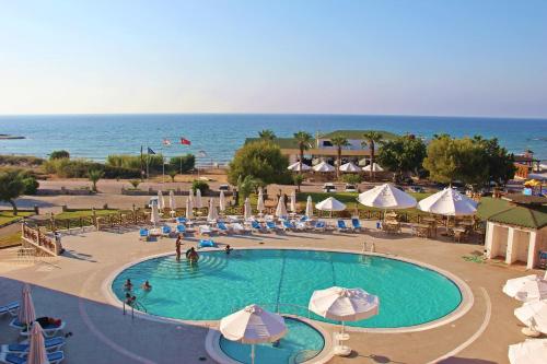 a large swimming pool with umbrellas and the ocean at Kaplica Hotel in Famagusta