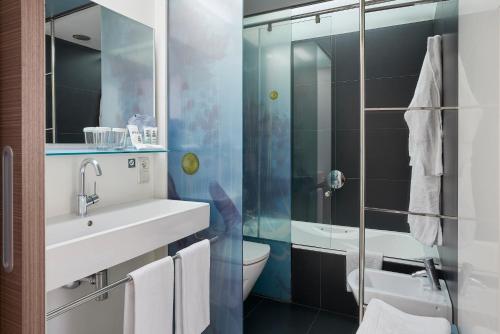 ein Bad mit einem Waschbecken, einem WC und einer Dusche in der Unterkunft Vincci Zaragoza Zentro in Saragossa