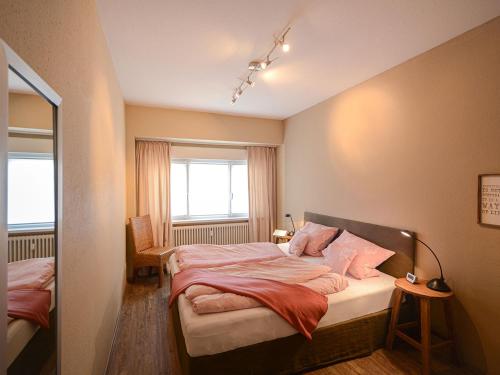 Schlafzimmer mit einem Bett mit rosa Kissen und einem Fenster in der Unterkunft ABACCO Ferienwohnungen in Überlingen