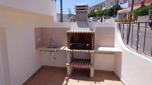 eine Küche mit einer Spüle und einer Bank auf dem Balkon in der Unterkunft Nunes Apartments in Mexilhoeira da Carregacao