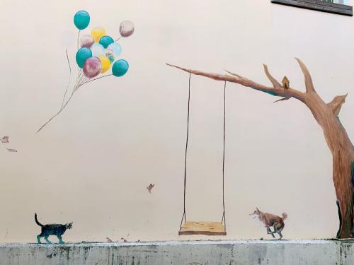 two cats walking on a wall with balloons and a tree at Backstreet Inn in Xiluo