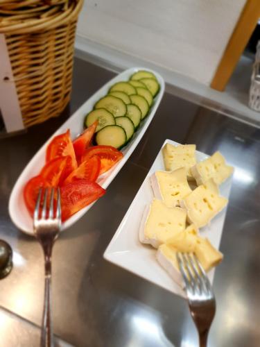 two plates of cheese and vegetables on a counter with forks at Aparthotel Wangener Landhaus in Stuttgart