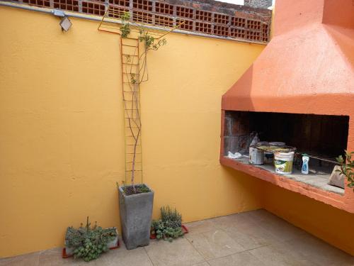 a building with a yellow wall with a fireplace at Monoambiente en Colonia in Colonia del Sacramento