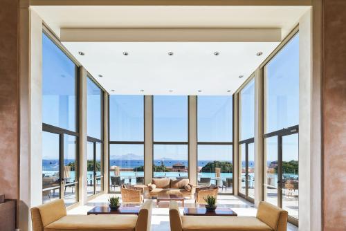 a living room filled with furniture and large windows at Atlantica Belvedere Resort - Adults Only in Kardamaina