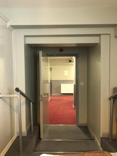 a hallway with a door leading to a room with a red carpet at Al Forno Restaurant & Inn in Norwich
