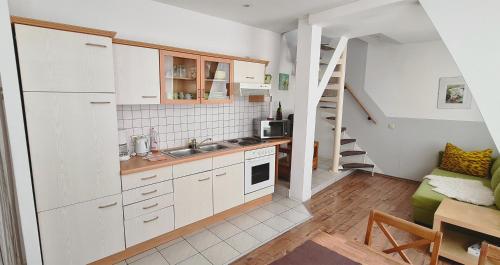 a small kitchen with white cabinets and a staircase at Altstadtfreude Stralsund in Stralsund
