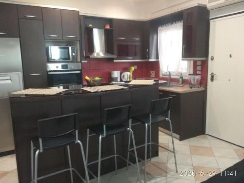 a kitchen with black cabinets and black bar stools at Soyzana heavenly home in Néa Kerasiá