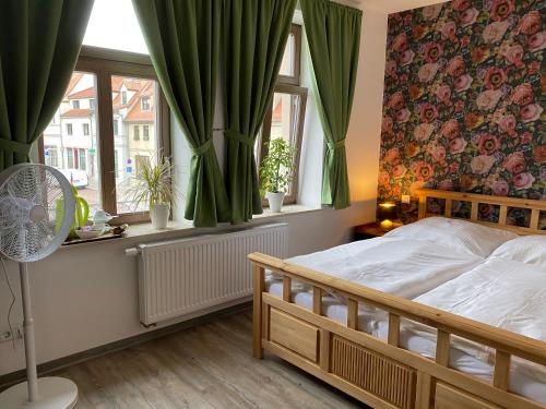a bedroom with a bed and windows with green curtains at Restaurant & Pension Stadtscheune in Köthen