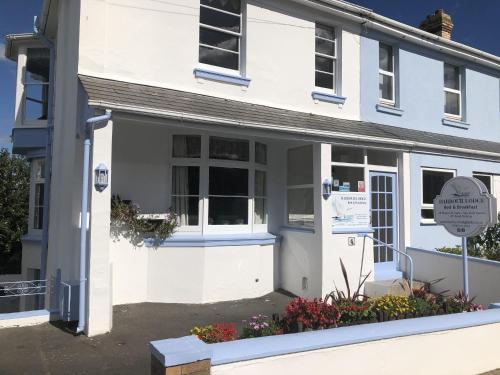 a white house with a sign in front of it at Harbour Lodge B&B in Paignton