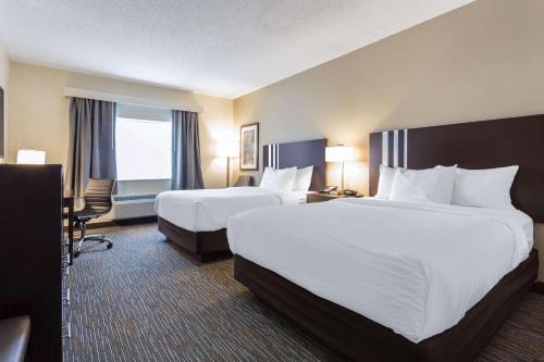 a hotel room with two beds and a desk at Wingate by Wyndham Gurnee in Gurnee