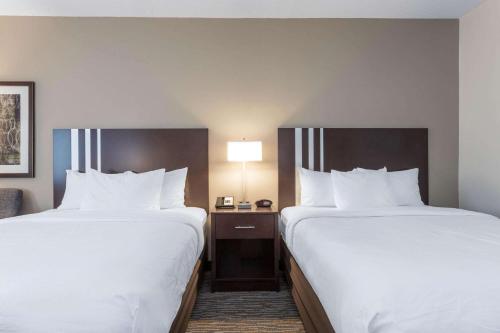 two beds in a hotel room with white sheets at Wingate by Wyndham Gurnee in Gurnee