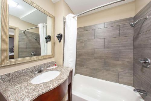 y baño con bañera, lavamanos y ducha. en Super 8 by Wyndham Pensacola NAS Area, en Pensacola