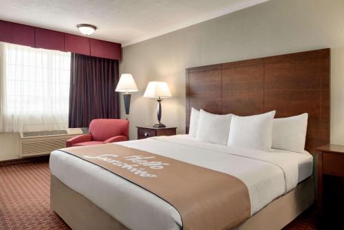 een hotelkamer met een groot bed en een rode stoel bij Days Inn by Wyndham Whitmore Lake in Whitmore Lake