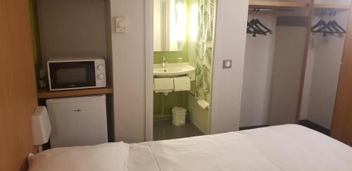 1 dormitorio con 1 cama y baño con lavamanos en Kyriad Direct Poitiers - Gare du Futuroscope en Chasseneuil-du-Poitou