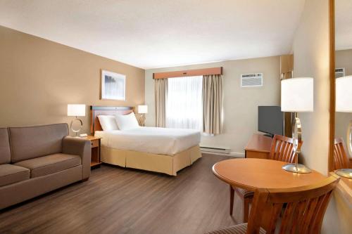 a hotel room with a bed and a couch and a table at Days Inn by Wyndham Nanaimo in Nanaimo