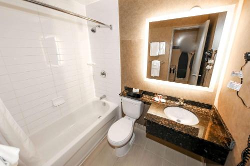a bathroom with a toilet and a sink and a tub at Howard Johnson by Wyndham Winnipeg West in Winnipeg