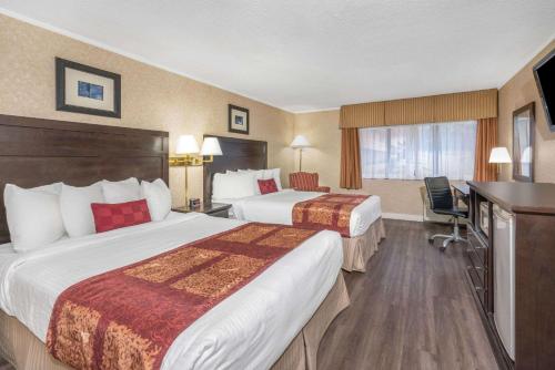 a hotel room with two beds and a television at Ramada by Wyndham Coquitlam in Coquitlam