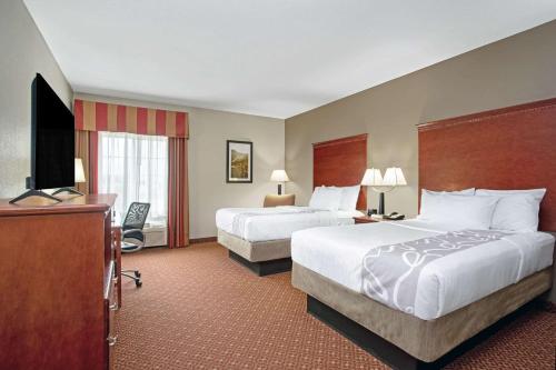 a hotel room with two beds and a flat screen tv at La Quinta by Wyndham Fairfield TX in Fairfield