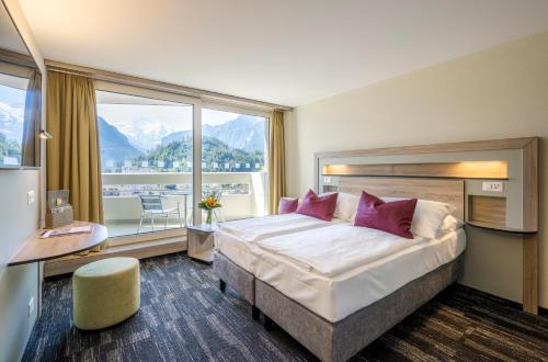 a hotel room with a bed and a large window at Metropole Swiss Quality Hotel in Interlaken