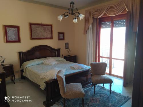 a bedroom with a bed and two chairs and a window at Casa vacanze a Serra Scirocco in Trabia