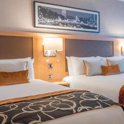 a hotel room with two beds and a tv on the wall at Clayton Hotel, Manchester Airport in Hale