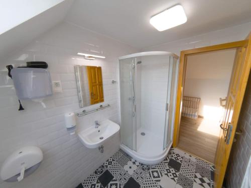 a white bathroom with a shower and a sink at Kun Pista Vendégház in Vértesboglár