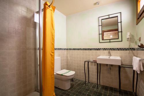 a bathroom with a toilet and a sink and a mirror at Hostal Los Canteros in Golmayo