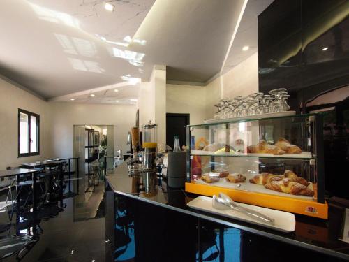 een restaurant met een toonbank met een vitrine vol gebak bij Hotel Versailles in Colorno