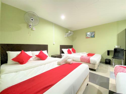 a hotel room with two beds with red and white pillows at OYO 873 Bamboo Inn in Batu Ferringhi