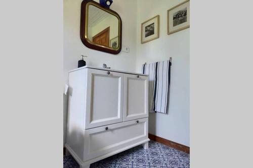 La salle de bains est pourvue d'une armoire blanche et d'un miroir. dans l'établissement La isla de las sirenas, à Oruña