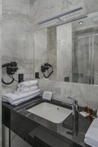 a bathroom with a sink and a mirror and towels at Hotel & Restauracja Gniecki in Hrubieszów