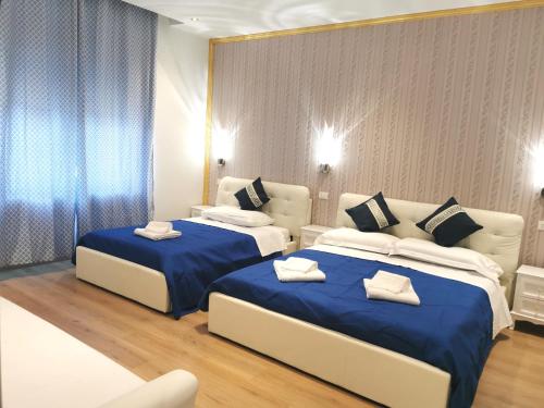 two beds in a hotel room with blue sheets at fiera camera in Verona